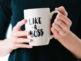 A woman holding a with cup with like boss text on it